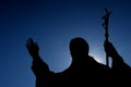 Silhouette of sculpture of pope John Paul The Second, with sun shining from behind