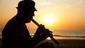 Silhouette of senior man playing bamboo flute on the beach at sunset Royalty Free Stock Photo