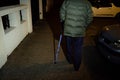 Silhouette of senior man walking on French street at night using walking stick