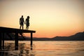 Silhouette of sensual couple stand on pier with sunset above sea surface on background. Couple in love on romantic date Royalty Free Stock Photo