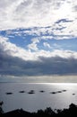 Silhouette of several little boats drifting in the ocean.