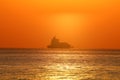 Silhouette of a ship in the water with the horizon and the golden sunset sky in the background Royalty Free Stock Photo