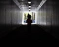 Silhouette shot of a little girl in the middle of dark tunnel with lights Royalty Free Stock Photo