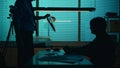 Silhouette shot of a perpetrator or prisoner sitting in the interrogation room in front of the detective. The policemnan