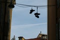 Silhouette shot of two pairs of shoes hanging on the wire attached to two opposite buildings.