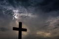 Silhouette of a simple catholic cross, dramatic stormclouds after heavy rain