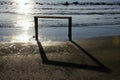 Silhouette of a simple wooden structure in the sea with its shadow on the shore and the reflection of the rays of the setting sun