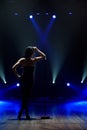 Silhouette of singer standing on stage at microphone in night club. Royalty Free Stock Photo