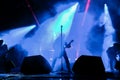 Silhouette of a singer vocalist and guitar player performing at a concert in the fog. Dark background, smoke, concert spotlights