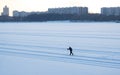 Moscow. The silhouette of a skier goes into the distance skiing on snow in a wide bed of a frozen river in the city.