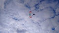 Silhouette of a skydiver in the sky against a blue sky with white clouds with a multicolored parachute Royalty Free Stock Photo