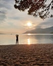 Silhouette of a slender woman looking at the sunset, which stands on the seashore. Enjoying a relaxing summer vacation