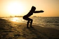 Silhouette of slim sporty girl exercising on the beach during sunset. Royalty Free Stock Photo