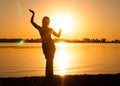 Silhouette of slim woman dancing tribal dance on beach