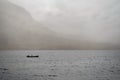 Silhouette of a small fishing motor boat in a lake, Huge mountain covered with fog in the background. Connemara, Ireland Royalty Free Stock Photo