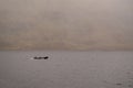 Silhouette of a small fishing motor boat in a lake, Huge mountain covered with fog in the background. Connemara, Ireland Royalty Free Stock Photo