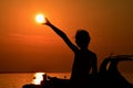 Silhouette of small girl holding sun during sunset above marina, part of motor boat visible on right side Royalty Free Stock Photo