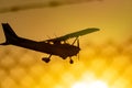 Silhouette of small propeller plane landing or taking off on the runway backlit under a yellow sun with the mountain Royalty Free Stock Photo