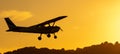 Silhouette of small propeller plane landing or taking off on the runway backlit under a yellow sun Royalty Free Stock Photo