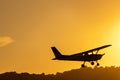 Silhouette of small propeller plane landing or taking off on the runway backlit under a yellow sun Royalty Free Stock Photo