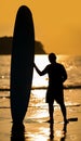 Silhouette Smart Asian Man long hair touches and poses with Standed Surfboard on the beach in Twilight time