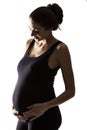 Silhouette of a smiling pregnant woman. Backlight. Isolated on a white background. Royalty Free Stock Photo