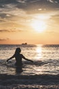 Silhouette of smiling woman on beach inside sea with her arms outstretched Royalty Free Stock Photo