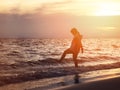 Silhouette smiling woman kicking water wave on the beach Royalty Free Stock Photo