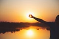 Silhouette of smiling young man holding his hand against sun on sunset near lake Royalty Free Stock Photo