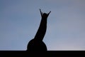 The silhouette of a snail raising its head against the blue sky