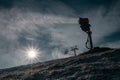 Silhouette of a snow cannon or artificial snow maker on a ski slope on a sunny day. Visible sun flare behind the exhaust of a