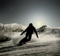 A silhouette of a snowboarder going down the slope in the opposing light
