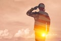 Silhouette of soldier with print of sunset and USA flag saluting on a background of light sky. Royalty Free Stock Photo