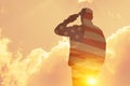 Silhouette of soldier with print of sunset and USA flag saluting on a background of light sky. Royalty Free Stock Photo