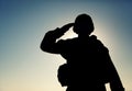 Silhouette of soldier salutes on sunset background