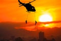 Silhouette Soldiers rappel down to attack from helicopter on with sunset and copy space add text Concept stop hostilities To pe