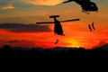 Silhouette Soldiers rappel down to attack from helicopter with sunset