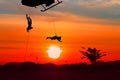 Silhouette Soldiers rappel down to attack from helicopter with warrior beware danger On the ground sunset Background blur and copy Royalty Free Stock Photo