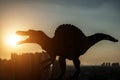 Silhouette of spinosaurus and buildings in a sunset time