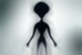 Silhouette of spooky alien and bright light on behind him