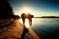 Silhouette of sport active adult man running and exercising on the beach. Calm water, island and sunny sky background. Royalty Free Stock Photo