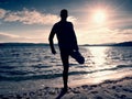 Silhouette of sport active adult man running and exercising on the beach. Calm water Royalty Free Stock Photo