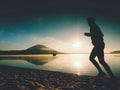 Silhouette of sport active man running on the lake beach at sunrise. Healthy lifestyle. Royalty Free Stock Photo