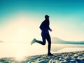 Silhouette of sport active man running on the lake beach at sunrise. Healthy lifestyle. Royalty Free Stock Photo