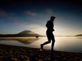 Silhouette of sport active man running on the lake beach at sunrise. Healthy lifestyle. Royalty Free Stock Photo