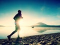 Silhouette of sport active man running on the lake beach at sunrise. Healthy lifestyle. Royalty Free Stock Photo