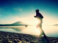 Silhouette of sport active man running on the lake beach at sunrise. Healthy lifestyle. Royalty Free Stock Photo