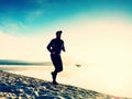 Silhouette of sport active man running on the lake beach at sunrise. Healthy lifestyle. Royalty Free Stock Photo
