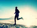 Silhouette of sport active man running on the lake beach at sunrise. Healthy lifestyle. Royalty Free Stock Photo