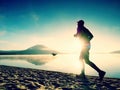 Silhouette of sport active man running on the lake beach at sunrise. Healthy lifestyle. Royalty Free Stock Photo